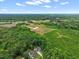 Expansive aerial view of property surrounded by lush forest and open fields under a partly cloudy sky at 9300 Glendora Ct, Garner, NC 27529