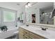 Bathroom with double sink vanity, tub, walk-in closet, and decorative mirror at 9300 Glendora Ct, Garner, NC 27529
