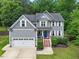Charming two-story home featuring gray siding, white trim, blue door, and a well-manicured lawn at 9300 Glendora Ct, Garner, NC 27529