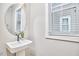 Modern powder room features a pedestal sink, oval mirror, and natural light at 941 W Club Blvd, Durham, NC 27701