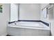 Bathroom featuring a luxurious tub with marble tile, blue trim, and a window with glass blocks at 102 Newell St, Chapel Hill, NC 27516