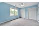 Light blue bedroom has gray carpet, a ceiling fan, and 2 closets, overlooking the yard at 102 Newell St, Chapel Hill, NC 27516