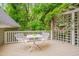 Outdoor deck area featuring a table and chairs, surrounded by lush greenery and a white trellis at 102 Newell St, Chapel Hill, NC 27516
