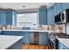 Kitchen features stainless appliances, blue cabinets, hardwood floors, and a marble tile backsplash at 102 Newell St, Chapel Hill, NC 27516