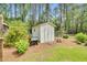 A white storage shed in the backyard with tool storage at 110 Phyllis Dr, Benson, NC 27504