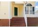 Charming front entrance with brick steps, green door, and arched window above white-framed window, adding curb appeal at 1211 Azalea Dr, Zebulon, NC 27597