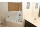 Bright bathroom featuring a soaking tub with tile surround and a vanity with black cabinets at 1333 Beaufort Dr, Graham, NC 27253