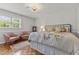 Bright bedroom with decorative floral bedding, two pink chairs, wood floors, and large window at 2190 Keith Hills Rd, Lillington, NC 27546