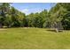 Expansive backyard with lush greenery, featuring a trampoline and a cozy fire pit area, perfect for outdoor fun at 2521 Georgianna Dr, Wake Forest, NC 27587