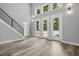 Bright living area with vinyl plank flooring, tall windows, and adjacent staircase at 2921 Wall Store Rd, Garner, NC 27529