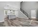 Open-concept living area with modern staircase and kitchen featuring gray island and white cabinets at 2921 Wall Store Rd, Garner, NC 27529