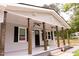 Charming front porch with dark wooden columns, ceiling fans, black door, and meticulously landscaped flower beds at 3030 Forrester St, Durham, NC 27704
