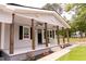 Inviting front porch featuring wooden columns, ceiling fans, black shutters, and a black front door at 3030 Forrester St, Durham, NC 27704