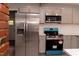 Close-up of the stainless steel refrigerator and modern range in the updated kitchen with gray cabinetry at 3030 Forrester St, Durham, NC 27704