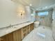 Spacious bathroom with double sink vanity, wood cabinets, marble countertops, decorative wall lighting, bathtub and tiled floors at 323 Hudson St, Raleigh, NC 27608