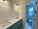 Bathroom featuring double sink vanity, quartz countertops, colored cabinets, decorative lighting and a partial view of the tub at 323 Hudson St, Raleigh, NC 27608