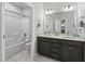 Bathroom with double vanity, gray cabinets, a large mirror, and a combined tub and shower at 359 Ashton Ridge Ln, Cary, NC 27513