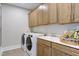 Bright laundry room features modern washer and dryer, ample cabinet space, and a convenient sink at 361 Murray Grey Ln, Wake Forest, NC 27587