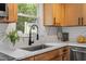 Modern kitchen sink with stainless steel appliances and stylish backsplash under a window with greenery outside at 3700 Summer Pl, Raleigh, NC 27604