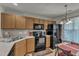 Bright kitchen featuring wood cabinets, black appliances, decorative lighting, and a charming dining area at 3806 Bison Hill Ln, Raleigh, NC 27604