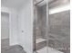 This shower features gray tiled walls, a glass enclosure, a shower seat, and a window for natural light at 436 Longleaf Glen Lane, Zebulon, NC 27597