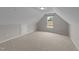 Large attic space with neutral carpet, access doors, a window, and walls painted in two-tone gray at 46 Blaze Ridge Dr, Smithfield, NC 27577