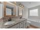 Bathroom featuring double granite vanity, decorative mirrors, and a soaking tub at 46 Blaze Ridge Dr, Smithfield, NC 27577