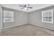 Neutral bedroom has gray walls, carpet, a ceiling fan, and natural light from two windows at 5002 Kendridge Dr, Durham, NC 27712