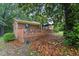 A charming brick home features a cozy deck surrounded by mature trees and a yard covered in colorful fall leaves at 5932 Johnson Pond Rd, Fuquay Varina, NC 27526