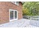 A private wooden deck with a set of white framed doors on a red brick house overlooking a lawn covered in fallen leaves at 6824 Branton Dr, Cary, NC 27519