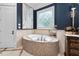 This primary bath features tile floors and a soaking tub with marble surround at 8308 Society Pl, Raleigh, NC 27615