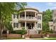 Stately two-story home featuring a double veranda, brick fence, beautiful landscaping, and black shutters at 8308 Society Pl, Raleigh, NC 27615