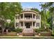 Stately two-story home featuring a double veranda, brick fence, beautiful landscaping, and black shutters at 8308 Society Pl, Raleigh, NC 27615
