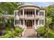 Stately two-story home featuring a double veranda, brick fence, beautiful landscaping, and black shutters at 8308 Society Pl, Raleigh, NC 27615
