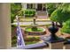 View of a charming tiered fountain in a landscaped yard, complemented by the inviting architecture of the home's entrance at 8308 Society Pl, Raleigh, NC 27615