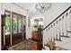 Grand foyer with hardwood floors, chandelier, staircase, front door, and decorative cabinet at 8308 Society Pl, Raleigh, NC 27615