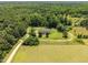 Picturesque aerial shot of a well-maintained home with a fenced yard surrounded by mature trees and open land at 921 Sweet Raspberry Lane Ln, Lillington, NC 27546