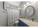 Well-lit bathroom with a granite-topped vanity, patterned shower curtain, and decorative round mirror at 925 Hidden Jewel Ln, Wake Forest, NC 27587