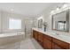 Well-lit bathroom with a soaking tub, tiled walk-in shower, and a double vanity with white countertops at 925 Hidden Jewel Ln, Wake Forest, NC 27587