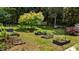 Expansive backyard with garden beds, a lush lawn, and privacy provided by mature trees at 925 S Chestnut St, Henderson, NC 27536