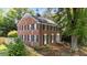 Charming brick two-story home showcasing a landscaped yard with mature trees at 925 S Chestnut St, Henderson, NC 27536