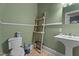 Charming powder room with a pedestal sink, toilet, and ladder storage rack at 925 S Chestnut St, Henderson, NC 27536