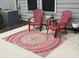 Relaxing patio space with red Adirondack chairs, vibrant rug, and quaint side table, perfect for outdoor lounging at 1008 Sounding Ln, Durham, NC 27703
