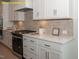 Modern kitchen featuring white cabinets, quartz countertops, stainless steel appliances, and stylish backsplash at 1036 Smoke Willow Way, Rolesville, NC 27571