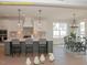 Open kitchen with white cabinetry, pendant lighting, gray island with seating, and an adjacent dining area at 1036 Smoke Willow Way, Rolesville, NC 27571