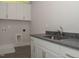 Laundry room with white cabinets, dark countertops, and tiled floors for functionality and style at 1036 Smoke Willow Way, Rolesville, NC 27571