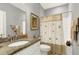 Well-lit bathroom with a granite countertop, neutral-colored walls, and a bathtub with a patterned shower curtain at 115 Thornwhistle Pl, Garner, NC 27529