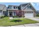 Charming home with a stone facade, manicured lawn, and an attached two car garage at 115 Thornwhistle Pl, Garner, NC 27529