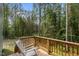 Wooden deck featuring a lone white rocking chair, offering a peaceful spot amidst the tall trees at 120 Rocking Horse Ln, Sanford, NC 27332