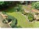 Aerial backyard view showcasing a tranquil pond with water lilies, surrounded by lush greenery, stone borders, and a fountain at 12212 Ashton Woods Ln, Raleigh, NC 27614